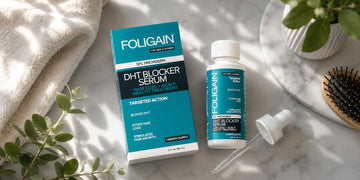 FOLIGAIN DHT շիճուկի տուփը, շիշը և կաթոցիկը մարմարե մակերեսի վրա՝ մազի խոզանակի կողքին։